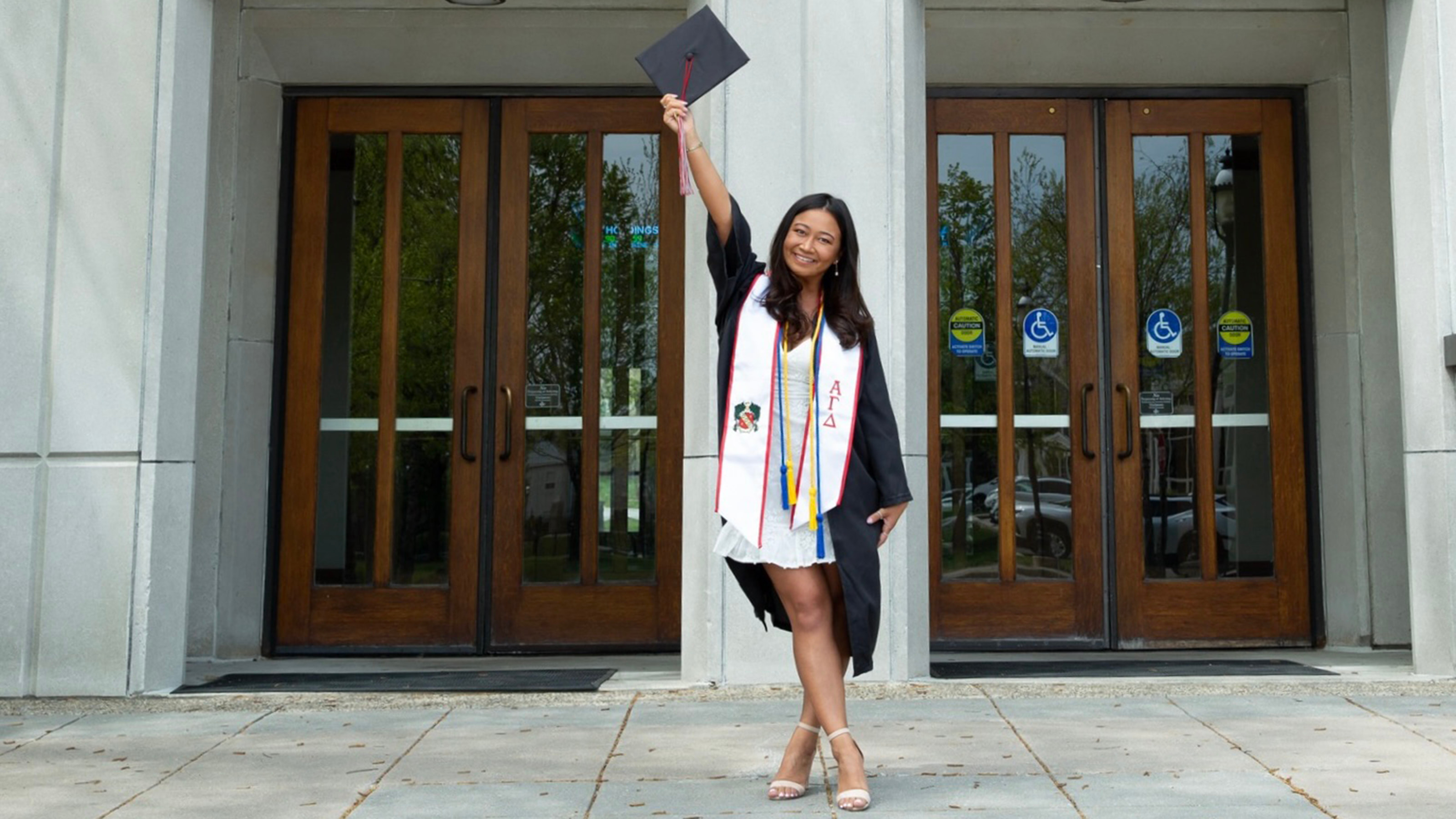 Theresa Luu in graduation attire in front of Mandeville Hall