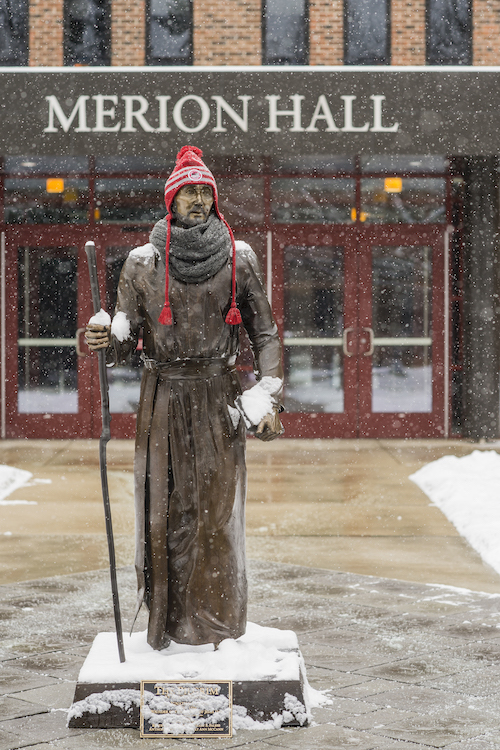 St Ignatius statue with a winter hat on as it snows