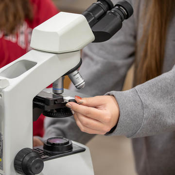 Female student using microscope in lab